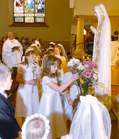 photo of Sydney Rabata placing flower in vase at foot of Blessed Virgin Mary statue during Mass at St. Joseph Parish in Baraboo