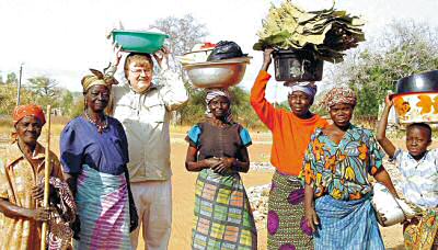 photo of Jeff Allen, principal of St. Bernard School in Watertown, getting a lesson in carrying vessels on his head during 2004 visit to Ghana