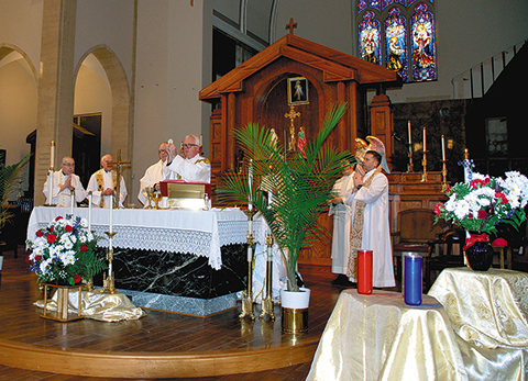 Bishop Donald J. Hying of Madison and priests from the Diocese of Madison, above, celebrate the Blue Mass beside the lit memorial candles. To the right, emergency personnel stand and pray during the Mass. (Catholic Herald photos/Angela Curio)