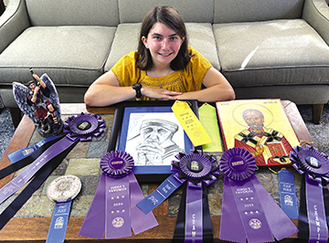 High school student Grace Marshall poses with each piece of Catholic art she’s submitted to the Dane County Fair. Two pieces, her drawing of St. Teresa of Calcutta and icon of St. Nicholas, have earned awards at the Wisconsin State Fair. (Contributed photo)